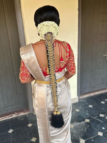 A simple and elegant muhurtham look. The off-white saree with a red border is paired with a classic braid adorned with temple jewellery and fresh flowers.
