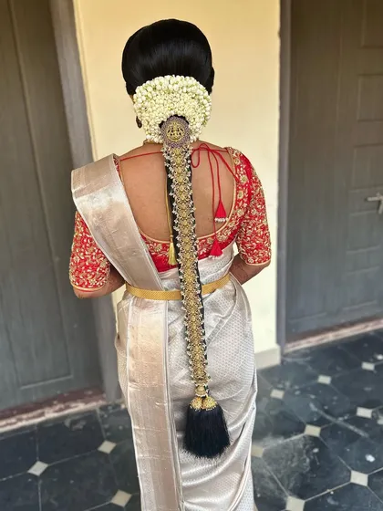 A stunning, long bridal braid adorned with a full set of antique-finish temple jewellery. This hairstyle is perfect for a bride wanting a grand and traditional look for her Muhurtham.