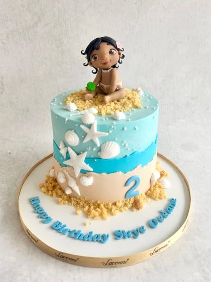 A sweet baby Moana cake for Skye's 2nd birthday. The design features a sandy beach, seashells, and a cute Moana figurine.