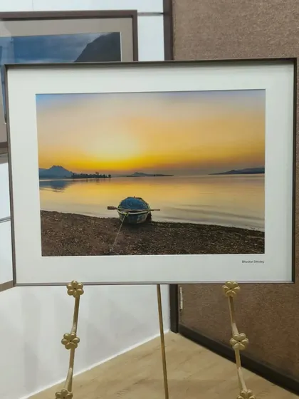 A serene sunset captured by photographer Bhaskar Sitholey. The warm, golden tones of the photograph are perfectly preserved in the print, and the simple black metal frame provides a classic, elegant finish.