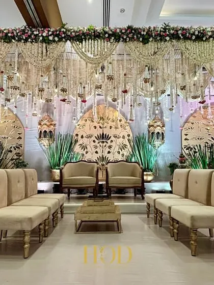 The stage is the heart of your celebration, and I make sure it's nothing short of spectacular. This expansive wedding reception stage features intricate golden laser-cut panels and cascading floral arrangements, creating a backdrop of pure opulence and grandeur.