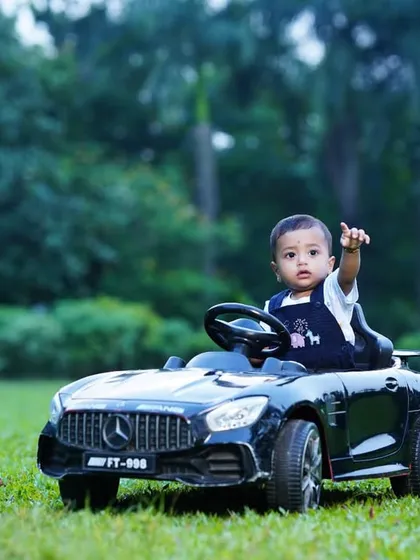 Pointing to the sky from his mini car, this little boy is on an adventure. Outdoor shoots provide a great canvas for action shots and playful poses.