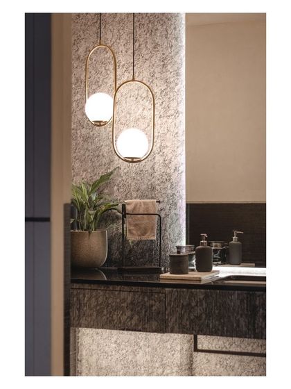 This powder room plays with multiple textures, from the rough stone vanity to the smooth brass pendant lights. The overall effect is cozy, moody, and sophisticated.