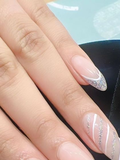 A close-up of a sophisticated French manicure variation with fine silver glitter lines creating a striped pattern on an accent nail.
