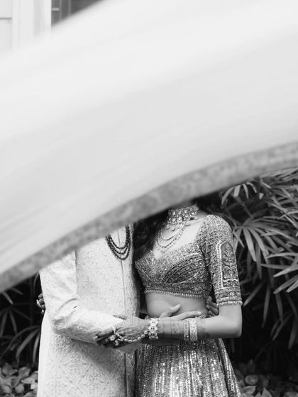 An abstract and romantic black and white shot of the couple, their forms partially obscured by a flowing veil or cloth.