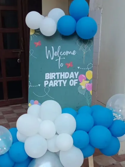 A charming welcome sign for a birthday party, decorated with a simple blue and white balloon garland.