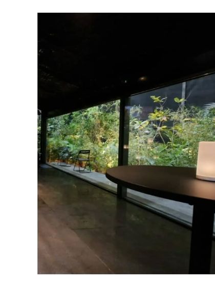 A view into the Durall Pavilion, where a single table lamp illuminates the dark, moody interior. The space was designed to showcase windows by creating an atmosphere of peace and focus.