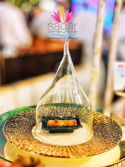 Presentation is key to the experience. Here, a delicate rose-infused baklava roll is presented under a glass cloche, creating a moment of drama and elegance for guests at a luxury wedding buffet.