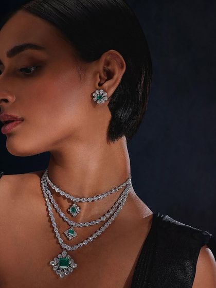 A close-up portrait showcasing the intricate design of Purab Paschim's emerald and diamond layered necklace and studs.