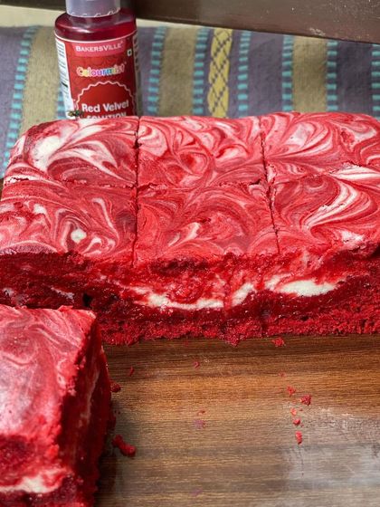 Sliced and ready to serve, these red velvet cheesecake brownies showcase the beautiful marbled pattern inside. They are perfect for adding a pop of color to any dessert platter.