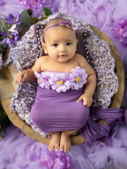 A little blossom. This baby, adorned with a floral wrap, looks so peaceful and content in her basket.