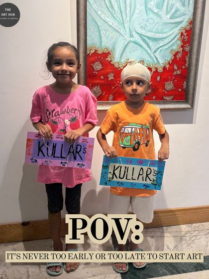 Art is for everyone, no matter how small. These two little artists are proudly holding up the signs they created, showcasing their budding creativity.