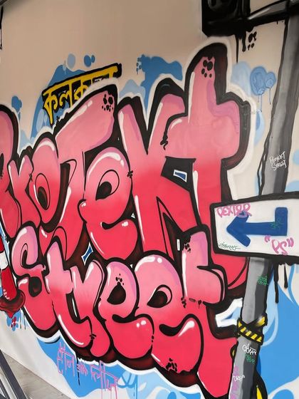 Another angle of the "Projekt Street" graffiti piece, showing how it wraps around the corner of the entrance. The design uses bright pinks and blues to create a bold, welcoming statement for the retail store.
