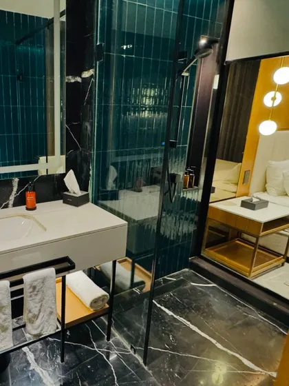 The quality of guest bathrooms is important. We check for modern fittings, cleanliness, and amenities, like this stylish bathroom with teal tiles and a glass shower.