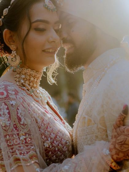 An artistic, sun-flared shot of the couple embracing. The strong backlight creates a dreamy and intimate feel, focusing on their connection.