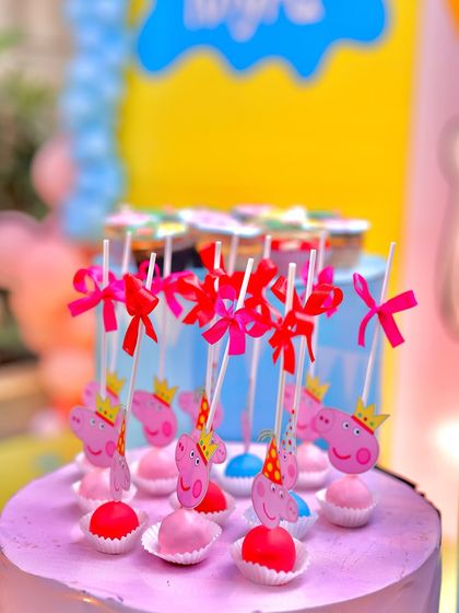 Sweet treats for a Peppaland party! These adorable cake pops are decorated with Peppa Pig characters, complete with little crowns and party hats, and tied with bright pink bows.