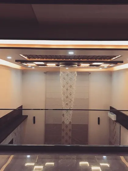 Looking down from the first-floor landing, you can appreciate the full impact of the double-height ceiling and the cascading chandelier. The glass railing ensures an unobstructed view.