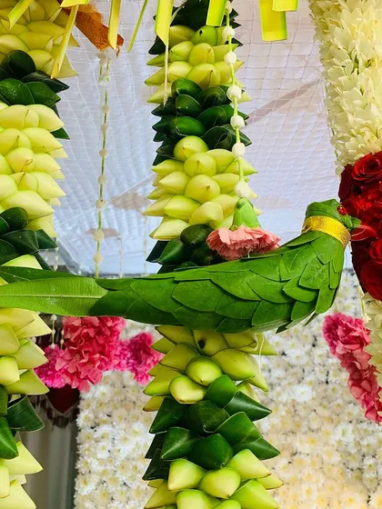 Our commitment to authenticity is in every detail. This close-up shows a parrot handcrafted entirely from fresh green leaves, a unique element we add to our traditional thorans and backdrops.
