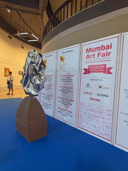 The sculpture stands tall in the exhibition hall, its reflective surface catching the light.