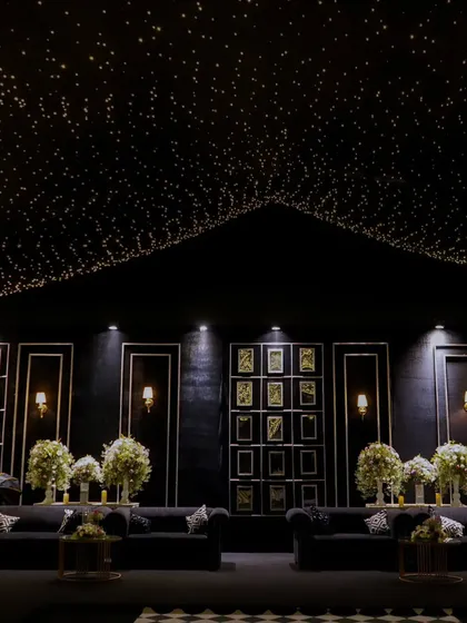 A wide view of the sophisticated lounge area, featuring plush black sofas, a starlit ceiling, and a gallery wall of memories, creating a chic and personal space for guests.