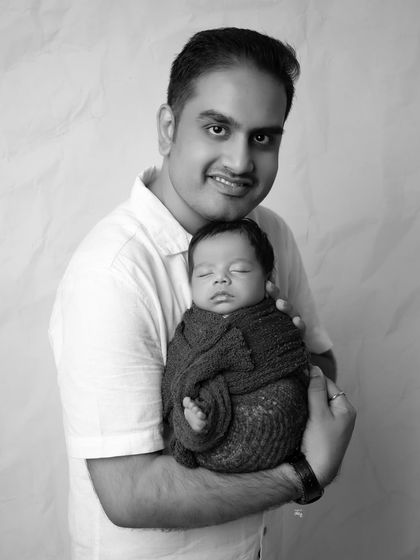 A proud father and his sleeping son in a classic black and white portrait. The simplicity of the color palette makes this a strong and timeless photograph.