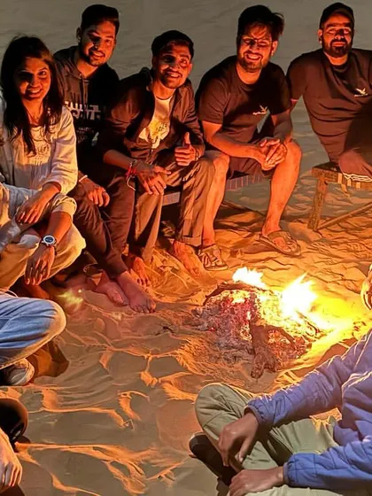 A group of travelers enjoying a bonfire in the Jaisalmer desert. The warmth of the fire and the company of new friends make for a perfect evening.