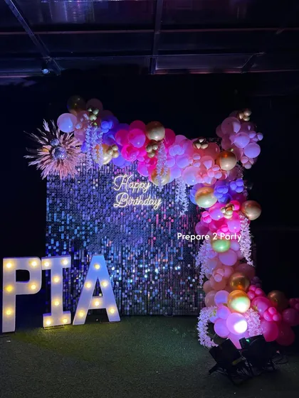 This glam birthday setup features a dazzling silver shimmer wall that catches the light beautifully. Paired with a custom neon sign, marquee letters, and a dramatic balloon garland, it creates a perfect, high-energy backdrop for photos.