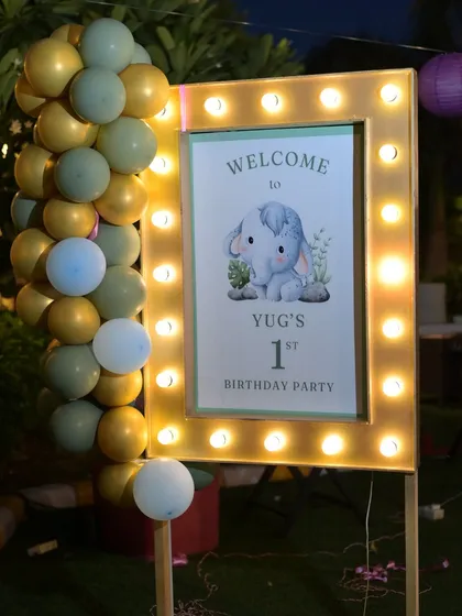The lit-up welcome sign for Yug's first birthday, featuring a cute baby elephant illustration.