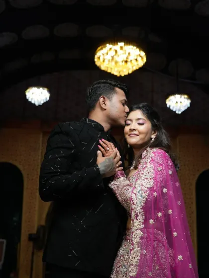 A romantic moment captured between the couple. Her makeup is flawless even in the low light, with a soft shimmer on the eyes and radiant skin.