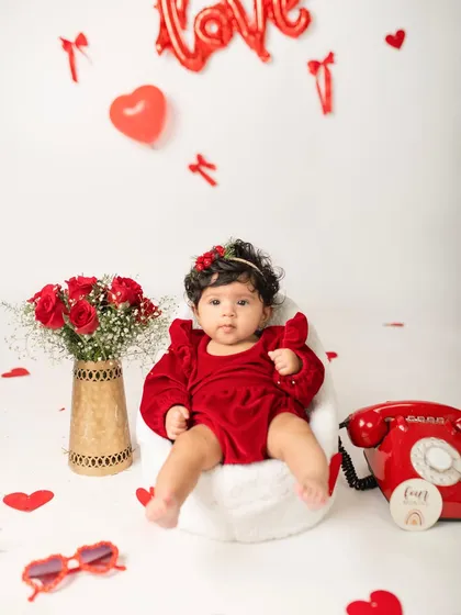 A full view of the Valentine's Day setup for a four-month milestone session, featuring red roses, hearts, and a very cute baby.