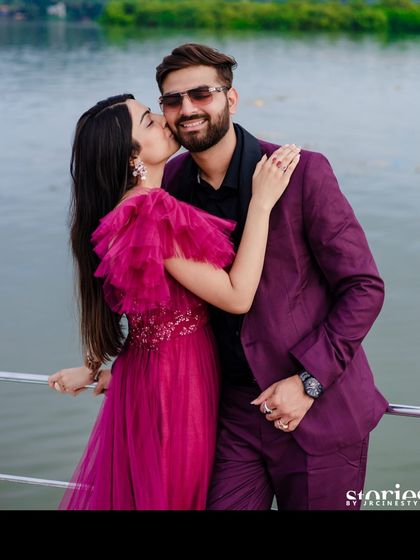 An intimate moment from the same photoshoot, with the woman in the magenta gown kissing the man's cheek.