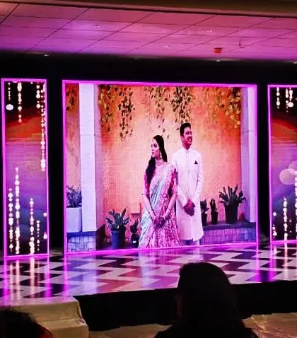 An impressive LED stage setup for a Sangeet night. The multiple screens display dynamic graphics and photos of the couple, creating a personalized and high-tech backdrop for the performances.