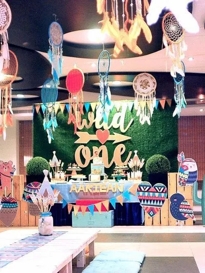 A "Wild One" tribal-themed birthday party. The decor featured a grass wall backdrop, dreamcatchers, and cute tribal animal cutouts for a fun and bohemian vibe.
