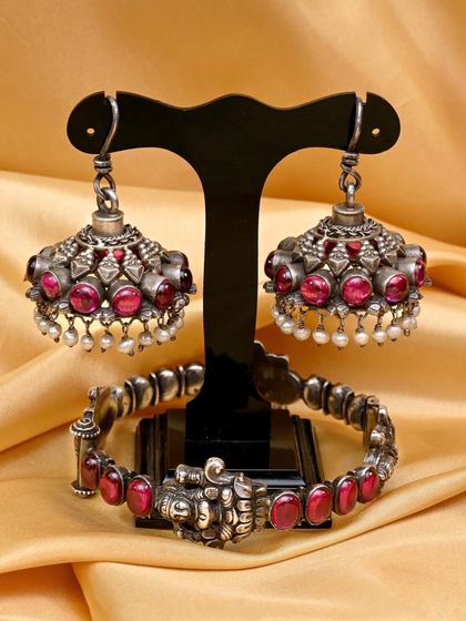 The jhumkha earrings and bracelet from the red stone set, arranged to showcase their complementary designs.