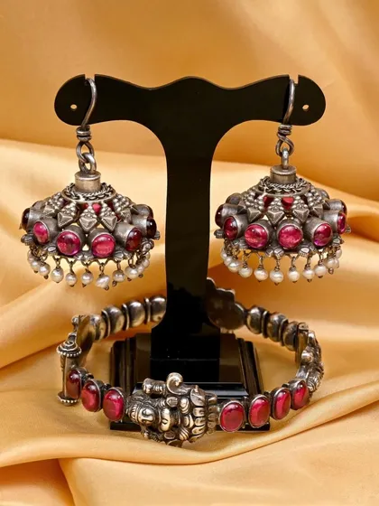 The complete set of silver jhumkhas and the matching bracelet. The bracelet features four seated goddess Lakshmi figures, adding an auspicious touch to the handcrafted set.