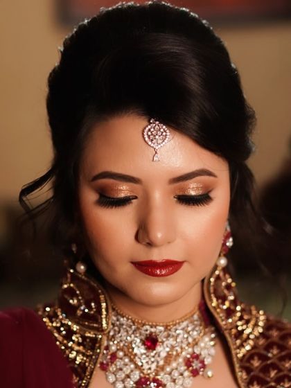 A truly classic bridal party look. The combination of luminous gold glitter on the eyes and a rich, glossy red lip creates a feeling of opulence and sophistication, perfect for an evening reception.
