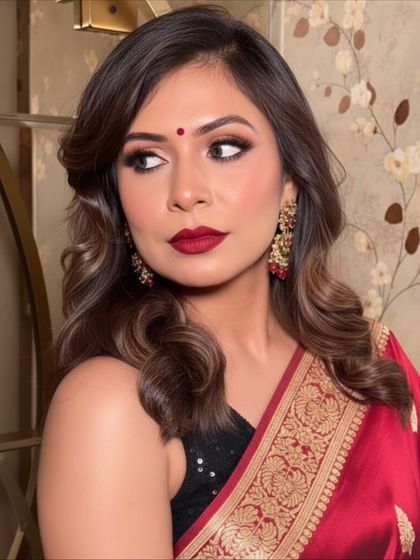 A festive look perfect for Navratri or any traditional celebration. This makeup features a classic red bindi, bold red lips, and defined smokey eyes that pair beautifully with a traditional saree.