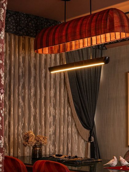 The custom chandelier, with its fabric-wrapped canopy, hangs above the client table, casting a warm glow. This shot highlights the layered drapery and the valance, which add a classic, theatrical element to this dramatic zone.