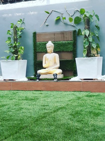 A peaceful corner for meditation, with a Buddha statue flanked by money plants growing on moss sticks.