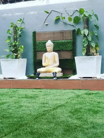 A peaceful corner for meditation, with a Buddha statue flanked by money plants growing on moss sticks.