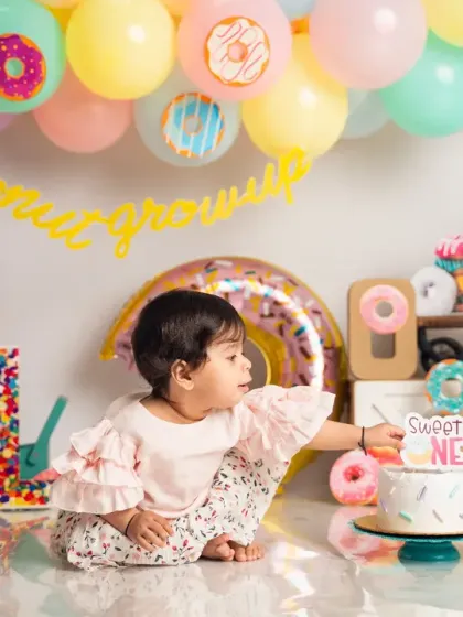 Reaching for the 'Sweet One' cake topper. This candid shot captures the anticipation and excitement of a first birthday cake smash.