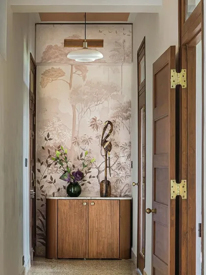 This corridor in Apartment 5026 creates a beautiful vista, drawing the eye towards a feature wall with scenic wallpaper. The reclaimed terrazzo floor and custom wood cabinetry add layers of texture and historical character.