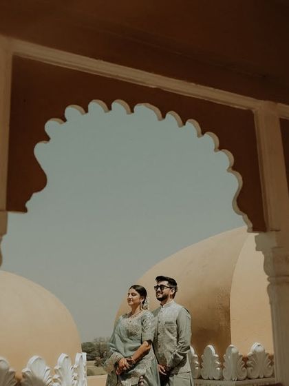 Framed by scalloped archways, the couple looks out towards the horizon. This beautifully composed shot uses architectural elements to create a sense of romance and shared dreams.