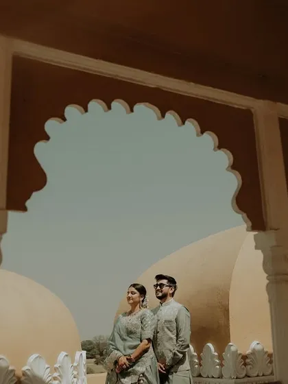 A wide shot that captures both the couple and the stunning scenery. Posing them between the pillars frames them perfectly, with the palace domes in the background telling the story of their destination wedding.