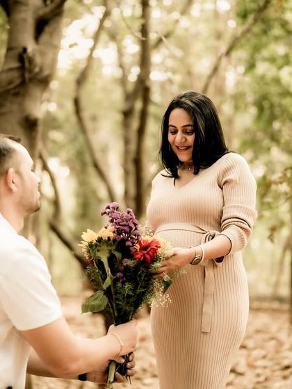 A chivalrous and romantic moment. He kneels to present her with a bouquet of flowers in the middle of a forest, a truly fairytale-like gesture.