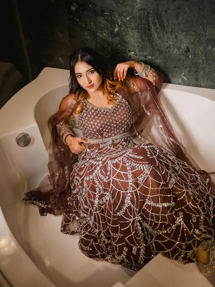 A close-up in the bathtub, showing the intricate details of the lehenga and makeup. This highlights the quality of the products and styling.