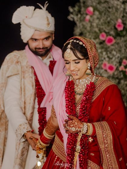 A quiet, candid moment of the couple walking hand-in-hand during their Pheras, sharing a smile.