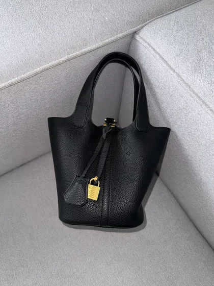 The HerCharm Bucket Bag in classic black. A must-have for any collection, this black version is sleek, versatile, and always in style.