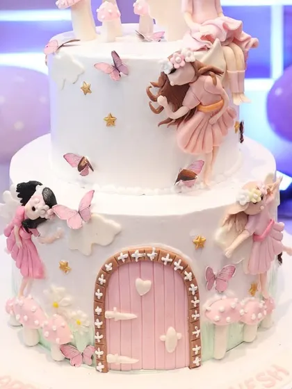 Even the cake is part of the story. This two-tiered masterpiece is adorned with intricate fairy figures, butterflies, and a magical door, perfectly matching the fairyland party theme.