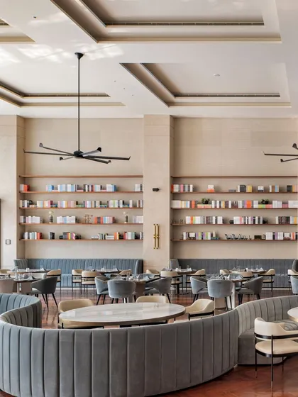 The graceful curves of the banquette seating soften the geometry of the large dining hall. This design choice not only adds visual appeal but also creates more fluid, sociable seating arrangements that encourage conversation among residents.